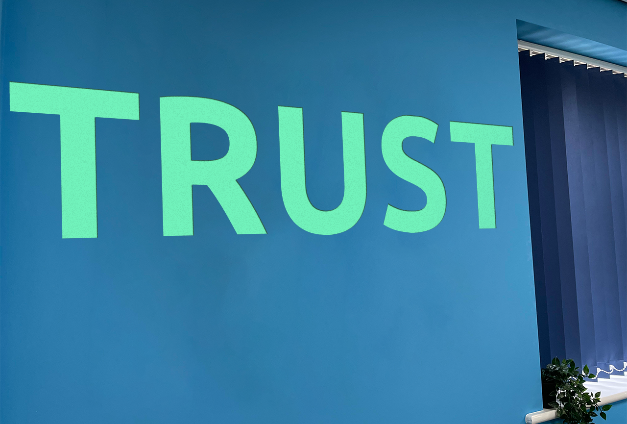 Blue mural that says 'trust' on our core values wall at Aspire CRM's UK office